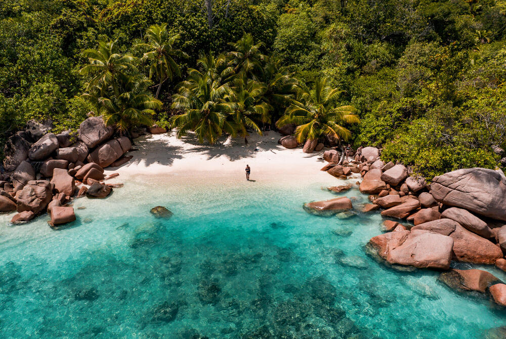 Anse Lazio Beach, Praslin, Seychelles solitary person on the white sands of Anse Lazio Beach, Praslin, Seychelles. Turquoise sea and rocks framing the beach, shot from above.