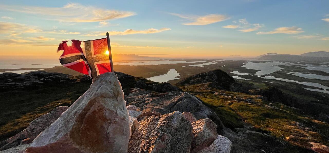 Norwegian flag in the sunset on top of the Torghatten mountain in Br&oslash;nn&oslash;ysund, Norway  