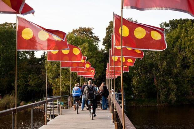 Biking over bridge with flags, Freetown Christiania