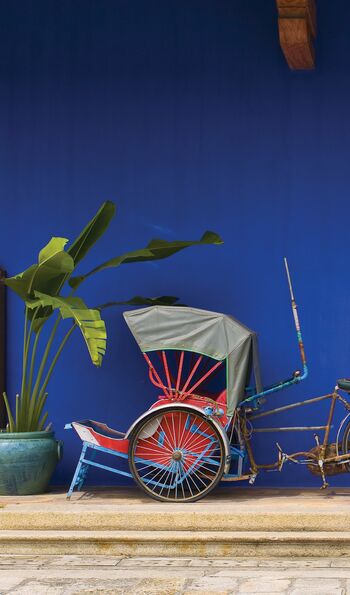 A cycle rickshaw against a blue wall in Georgetown, Penang, Malaysia