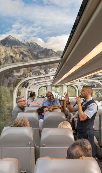 An onboard guide talking to passengers travelling in GoldLeaf service aboard Rocky Mountaineer