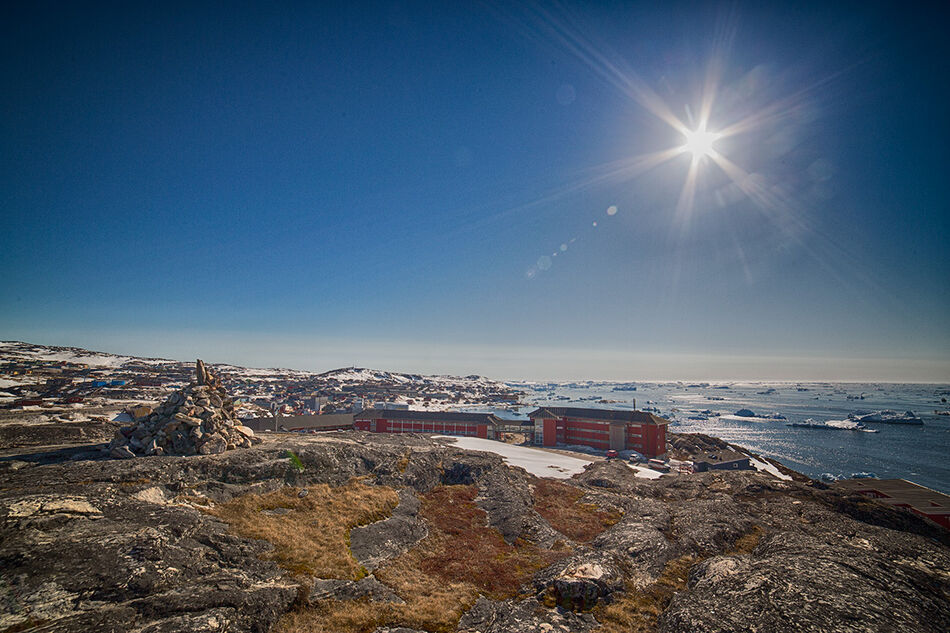 Hotel Arctic, Greenland A summertime view of Greenland's Hotel Arctic with shrubs in the foreground and icebergs in the sea behind.