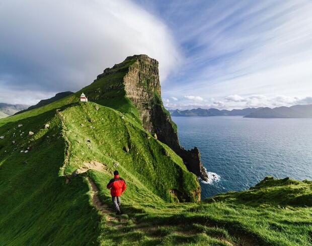 Hiker at Kallur Lighthouse on Kalsoy Island, Faroe Islands