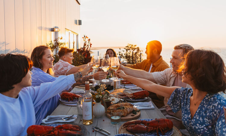 Friends dining on fresh lobster in New Brunswick at sunset, Atlantic Canada