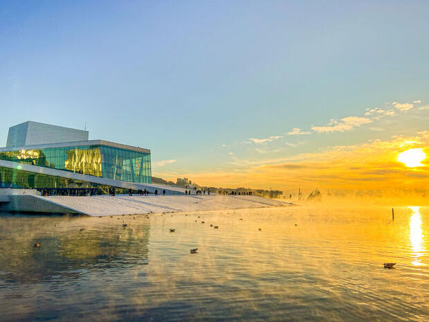  with Bright yellow sun reflecting on the glass of the striking architecture of the Oslo Opera House