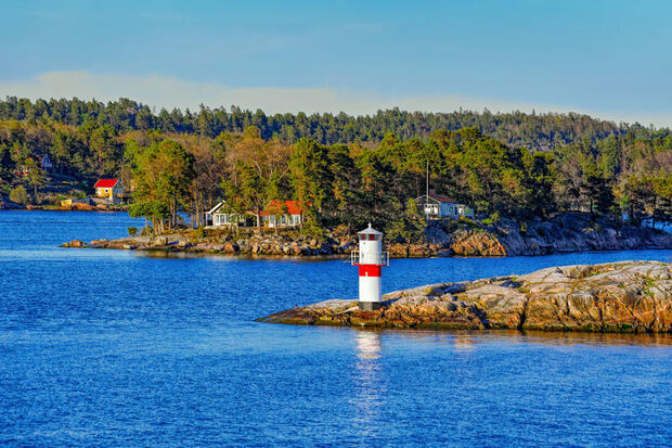 Image of lighthouse on rocky outcrop amid blue sea