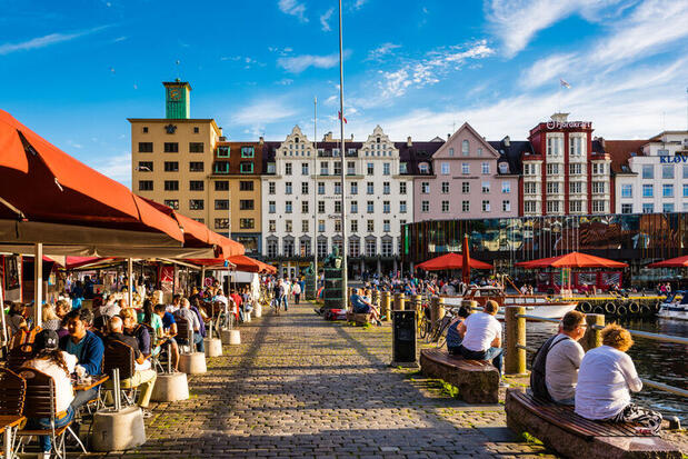 Bustling torget fish market with visitors eating on waterside benches