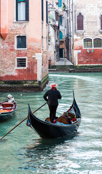 A traditional gondola on a Venetian canal, surrounded by classic Venetian houses